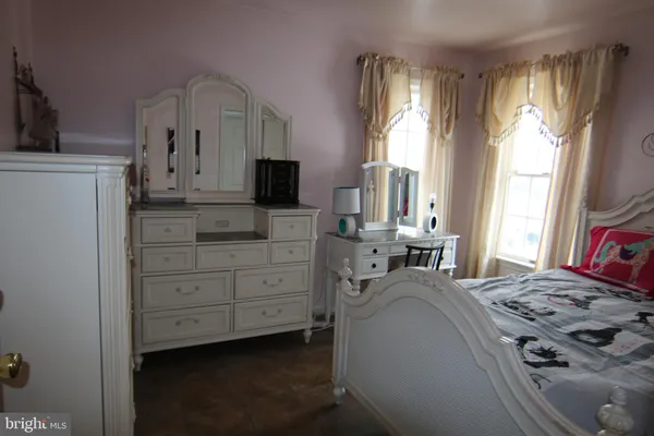 a bedroom with a bed a window and dresser