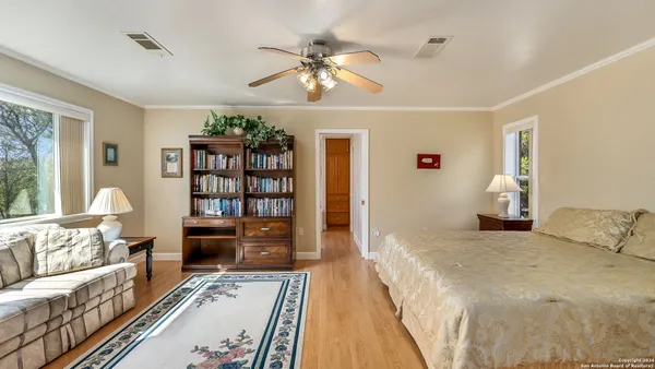 a spacious bedroom with a large bed a chandelier and a book shelf