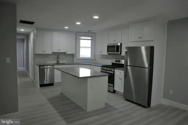 a kitchen with stainless steel appliances granite countertop a refrigerator a sink a stove a microwave and island