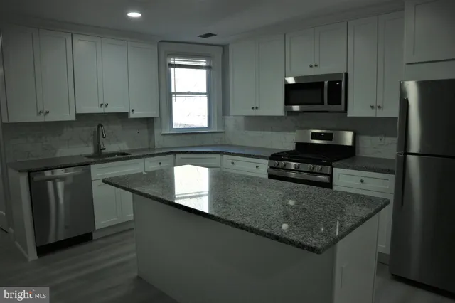 a kitchen with granite countertop stainless steel appliances a sink a stove a microwave a counter space and cabinets