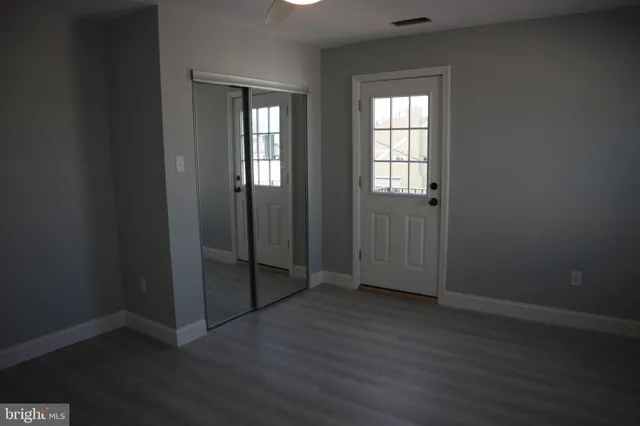 an empty room with wooden floor & closet area