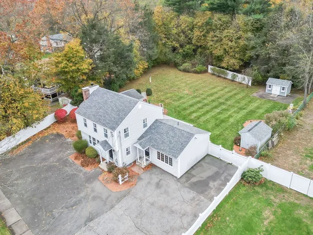 an aerial view of a house with garden space and trees all around