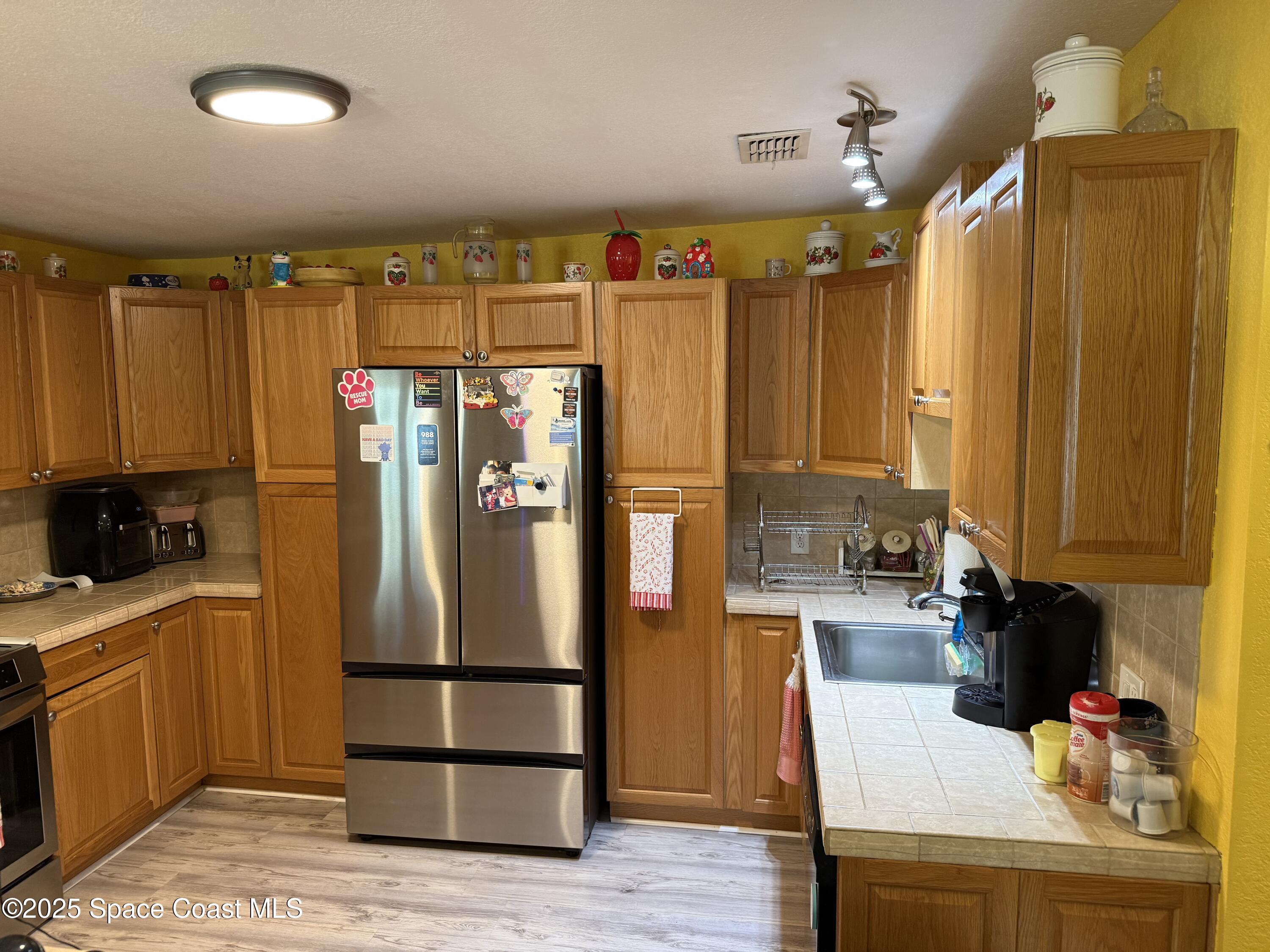 649 Waterside Road Southeast Palm Bay, FL 32909 - Photo 5 of 24 a kitchen with stainless steel appliances a refrigerator and a stove top oven