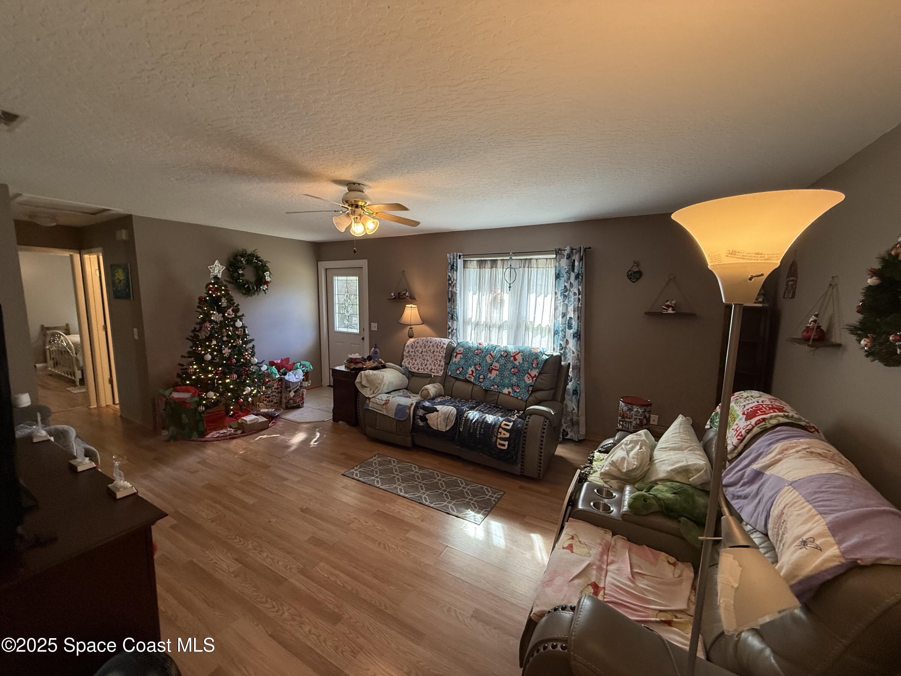 649 Waterside Road Southeast Palm Bay, FL 32909 - Photo 9 of 24 a view of a livingroom with furniture hardwood floor and a ceiling fan