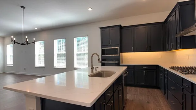 a view of an empty room with a kitchen and wooden floor