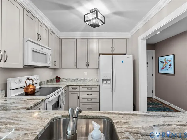 a kitchen with stainless steel appliances granite countertop a refrigerator a sink and white cabinets
