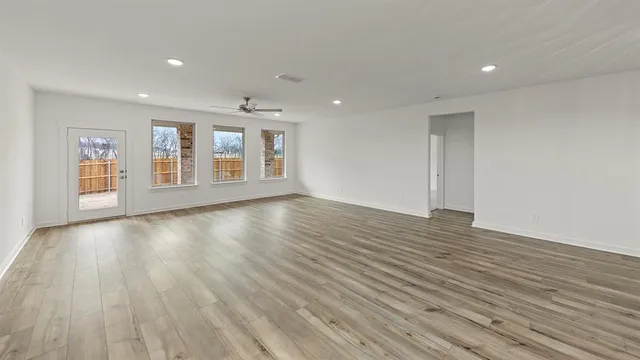 a view of an empty room with wooden floor and windows