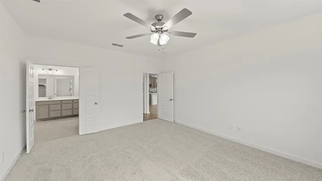 an empty room with chandelier fan and windows