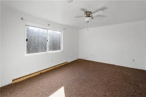 an empty room with a window and a ceiling fan