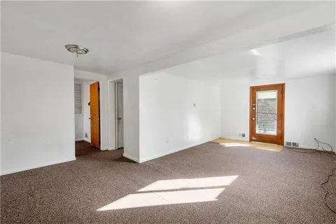 a view of an empty room with window and closet area