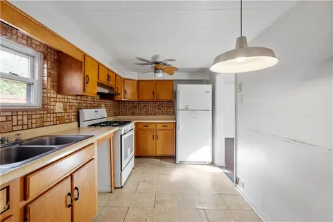 a kitchen with stainless steel appliances a sink a stove a refrigerator cabinets and a dining table