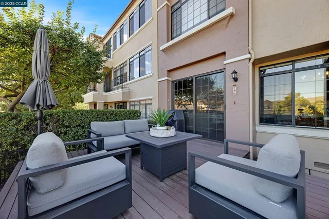 a view of a patio with couches table and chairs with wooden floor and fence