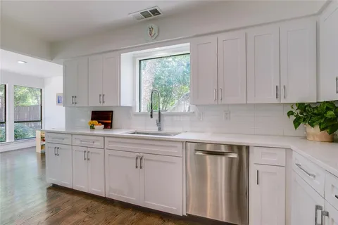 a kitchen with white cabinets and a window