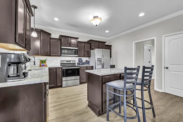 a kitchen with stainless steel appliances kitchen island granite countertop a table chairs microwave and sink