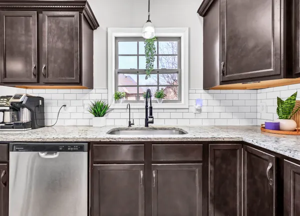 a kitchen with granite countertop stainless steel appliances a sink window and cabinets
