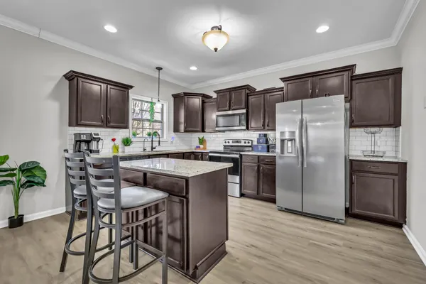 a kitchen with kitchen island a refrigerator stove microwave and cabinets