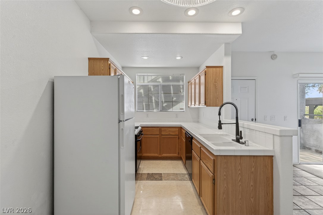 2201 Ramsgate Drive, Unit 1011 Henderson, NV 89074 - Photo 11 of 40 A well-lit kitchen with natural wood cabinetry and sleek white countertops.