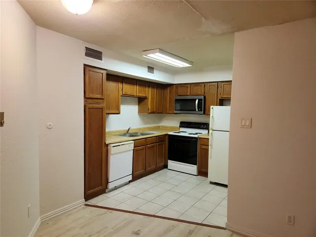 a kitchen with a sink a stove top oven and refrigerator