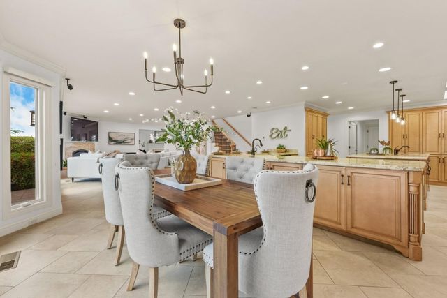 a kitchen with stainless steel appliances kitchen island granite countertop a table chairs and a refrigerator