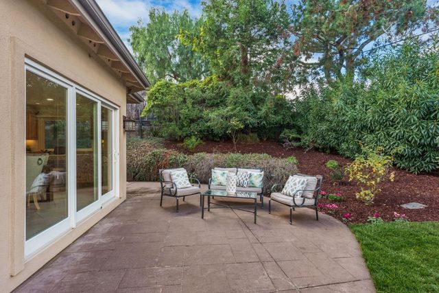 a view of backyard with seating space and trees in the back