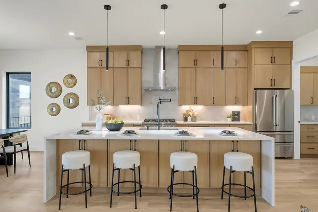 a kitchen with stainless steel appliances kitchen island granite countertop a dining table chairs and white cabinets