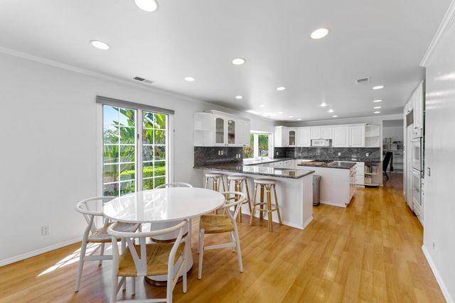 a kitchen with a dining table chairs and white appliances