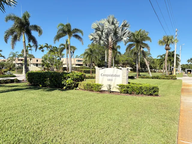 a view of a house with a yard and palm trees