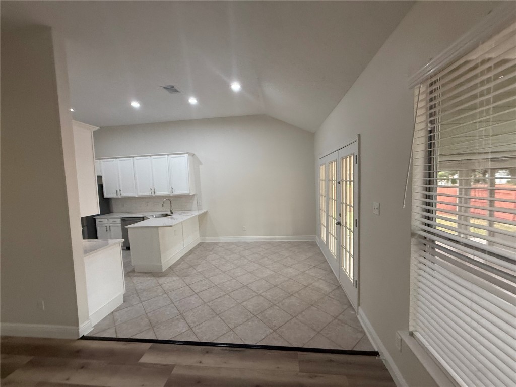 11711 Rydalwater Lane Austin, TX 78754 - Photo 10 of 20 Kitchen featuring white cabinets, a peninsula, lofted ceiling, recessed lighting, and light wood-style floors