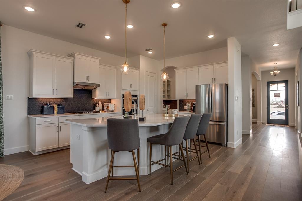 1437 Sun Gdn Way Justin, TX 76247 - Photo 4 of 28 a kitchen with stainless steel appliances kitchen island granite countertop a dining table chairs refrigerator sink and cabinets