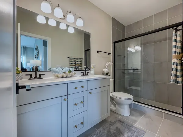 a spacious bathroom with a double vanity sink a toilet a mirror and shower