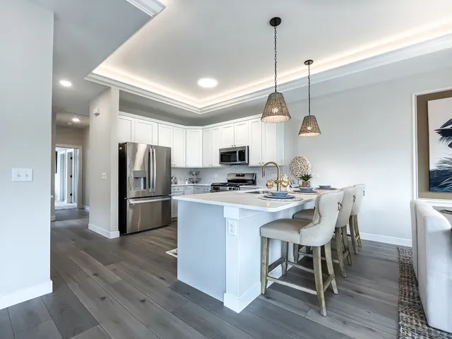 a kitchen with stainless steel appliances a dining table chairs stove refrigerator and cabinets