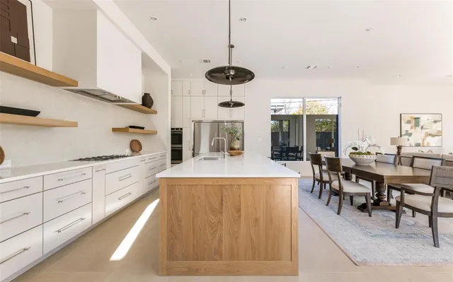 a large kitchen with kitchen island granite countertop a stove a sink a dining table and chairs with wooden floor