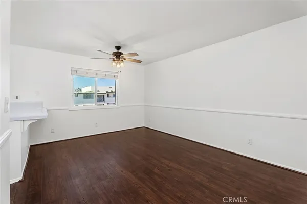 an empty room with wooden floor and chandelier fan