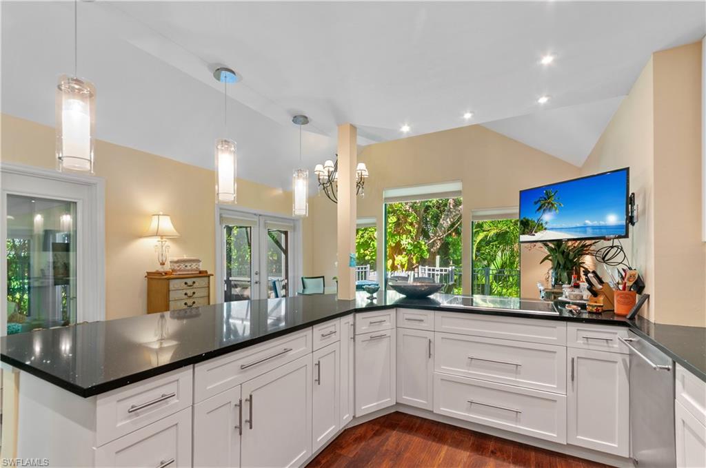 1313 Solana Road, Unit A3 Naples, FL 34103 - Photo 13 of 29 Kitchen with vaulted ceiling, hanging light fixtures, dark stone countertops, dark wood-type flooring, and white cabinetry