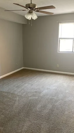 an empty room with windows and fan