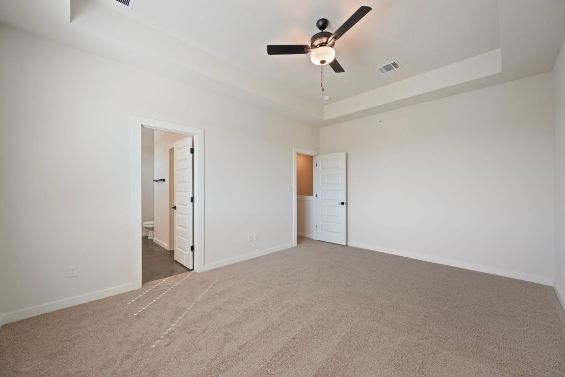 2600 Gattis School Road, Unit 1203 Round Rock, TX 78664 - Photo 14 of 25 Unfurnished bedroom featuring a tray ceiling, carpet flooring, ceiling fan, and connected bathroom