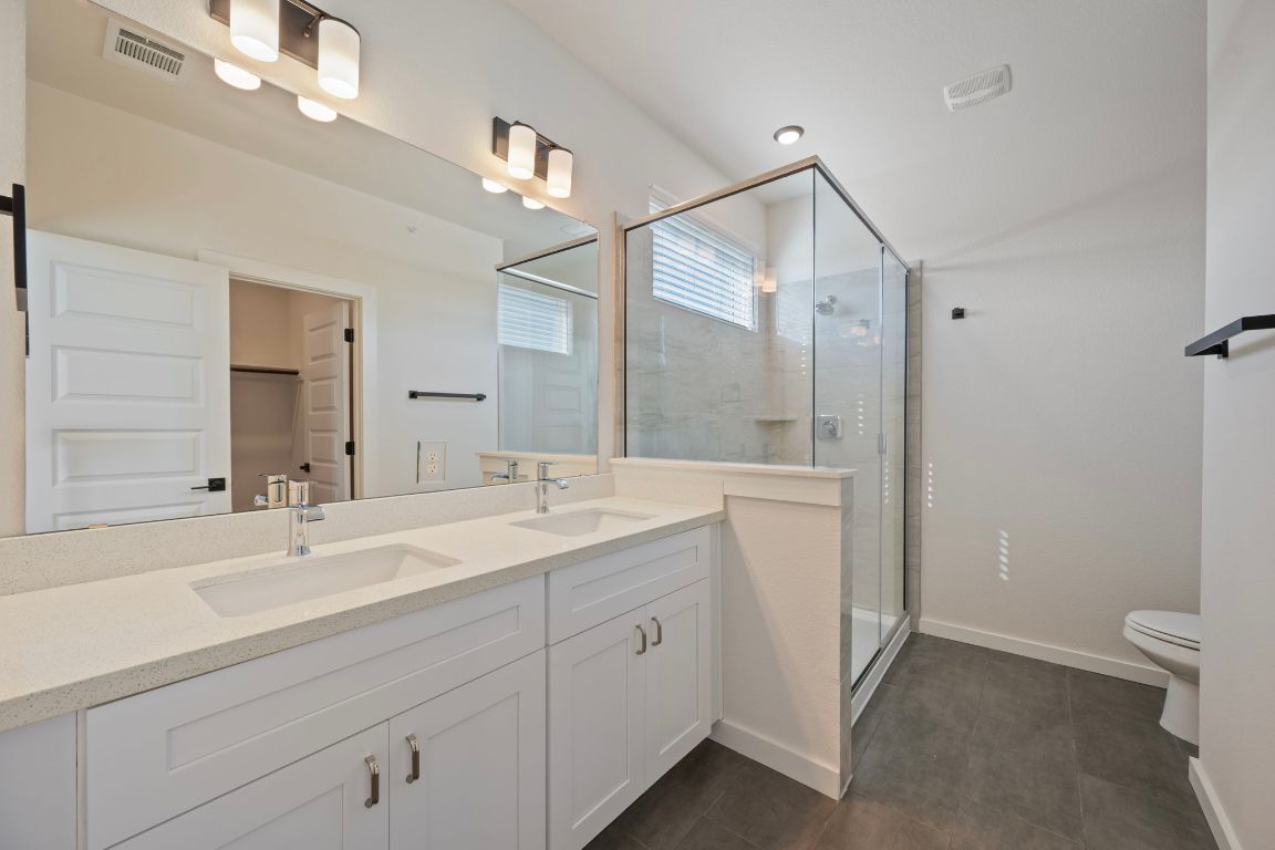 2600 Gattis School Road, Unit 1203 Round Rock, TX 78664 - Photo 15 of 25 Bathroom with a stall shower, a walk in closet, double vanity, and dark tile patterned floors