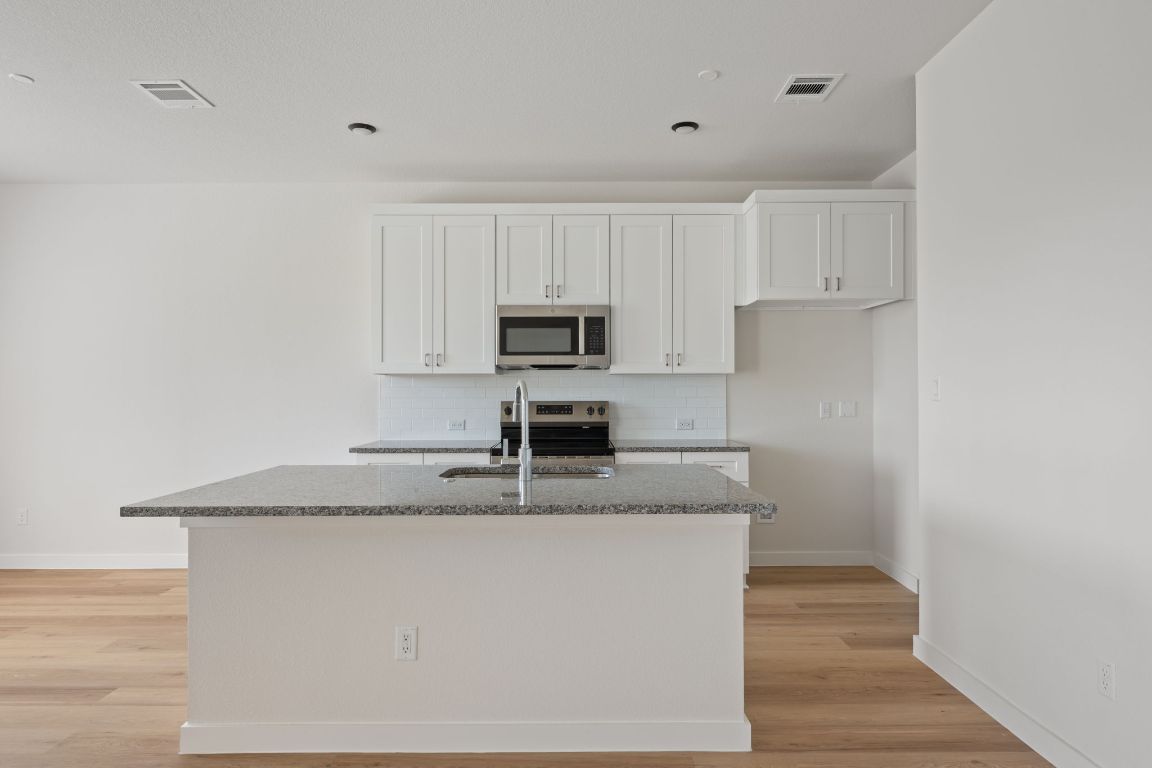 2600 Gattis School Road, Unit 1203 Round Rock, TX 78664 - Photo 6 of 25 Kitchen featuring tasteful backsplash, white cabinets, dark stone counters, stainless steel appliances, and light wood-style floors