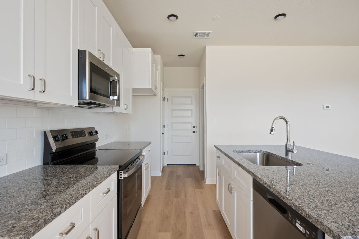 2600 Gattis School Road, Unit 1203 Round Rock, TX 78664 - Photo 8 of 25 Kitchen with stainless steel appliances, light wood-style floors, white cabinets, tasteful backsplash, and dark stone counters