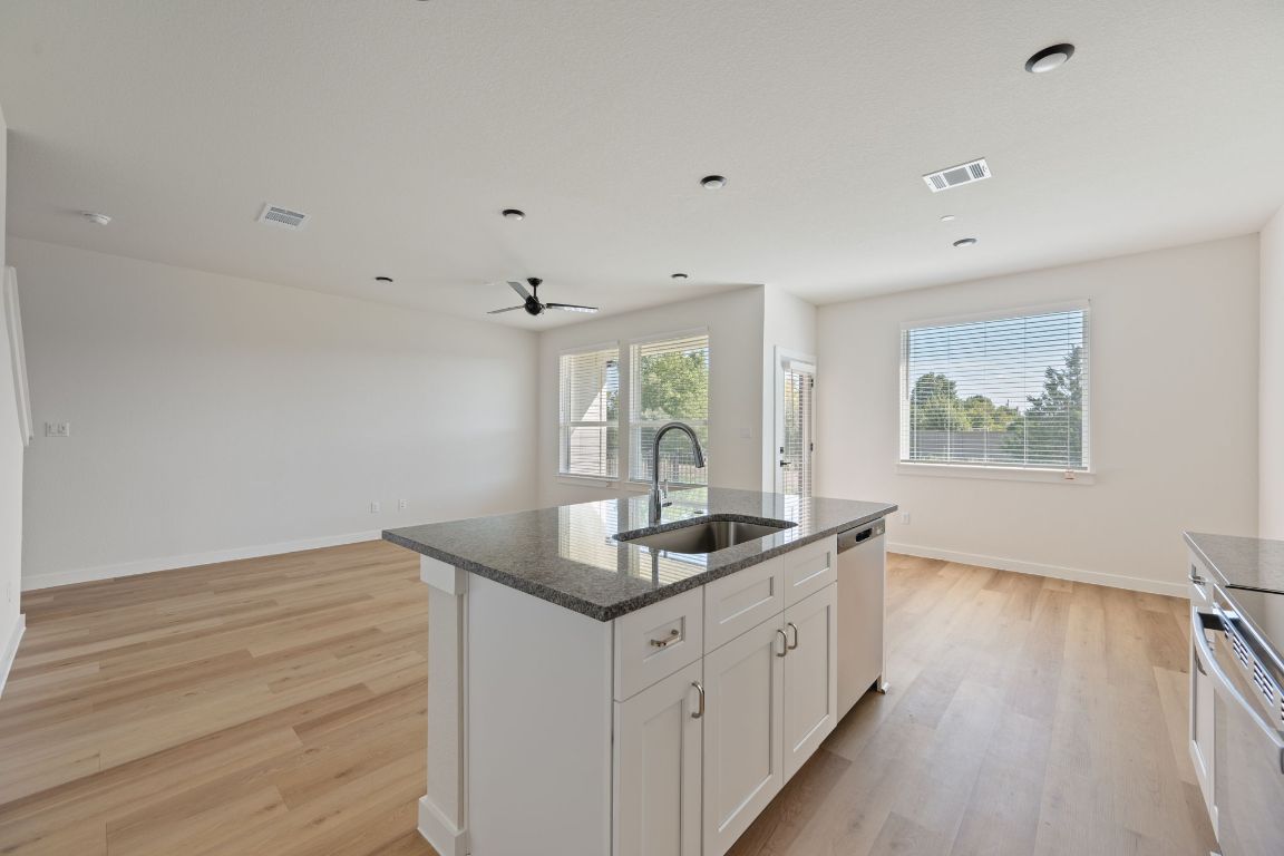 2600 Gattis School Road, Unit 1203 Round Rock, TX 78664 - Photo 9 of 25 Kitchen featuring dark stone counters, white cabinets, light wood-style flooring, appliances with stainless steel finishes, and a ceiling fan