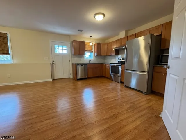 a kitchen with stainless steel appliances wooden floor and large window