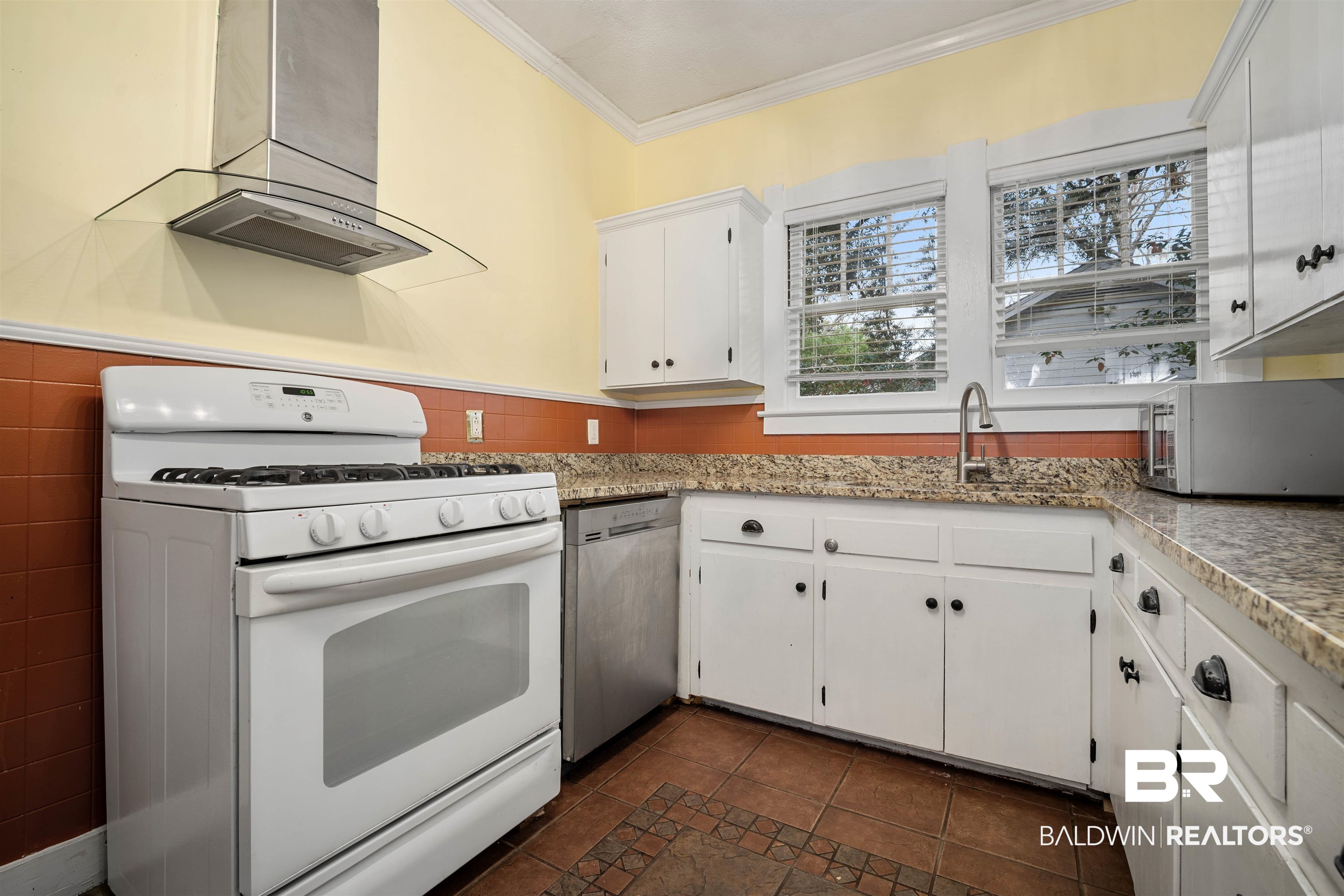118 Mohawk Street Mobile, AL 36606 - Photo 7 of 26 Kitchen with stainless steel appliances, ventilation hood, white cabinets, ornamental molding, and dark tile patterned floors