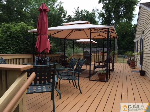 37 Academy Road Somerset, NJ 08873 - Photo 22 of 25 a view of deck with table and chairs under an umbrella with wooden floor