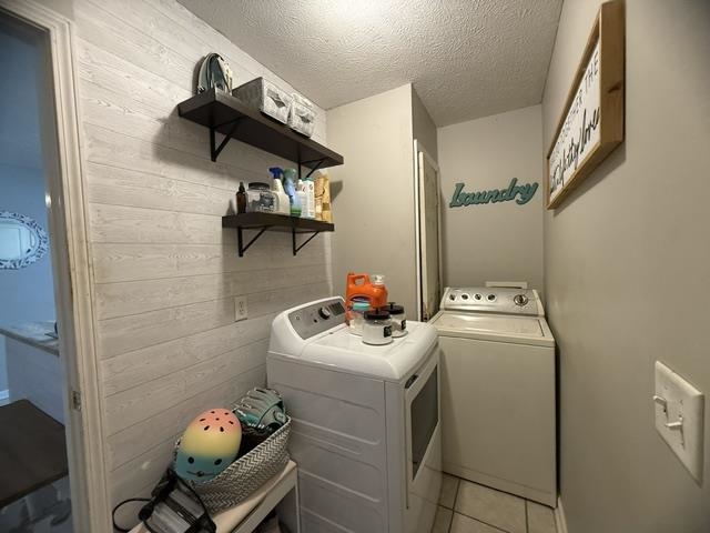395 Austin Street Savannah, TN 38372 - Photo 20 of 32 Laundry area featuring textured plank wall treatment, two floating shelves with dark wood-finish, light gray wall paint, and tiled flooring