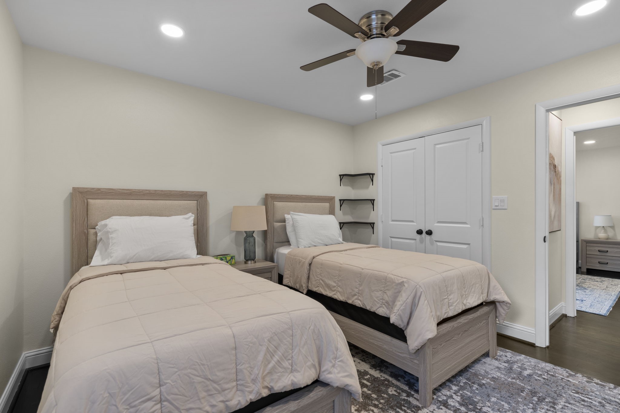 2402 Chimney Rock Road Houston, TX 77057 - Photo 27 of 36 Bright secondary bedroom with two twin beds, neutral finishes, and modern ceiling fan. Features a spacious closet, recessed lighting, and easy access to a beautifully updated bathroom—perfect for guests or shared living.