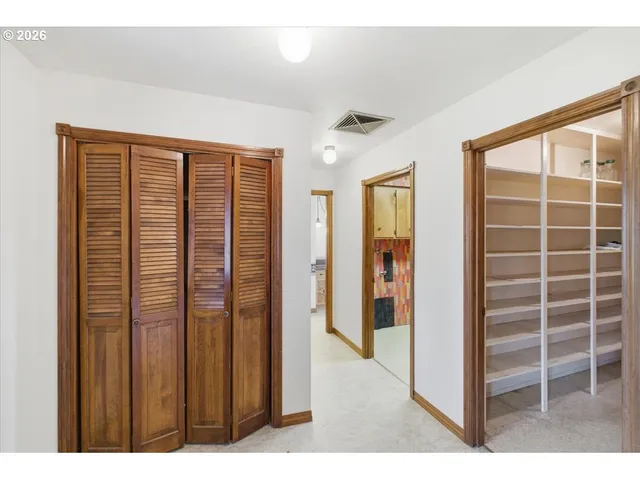 a view of an empty room with closet and a window