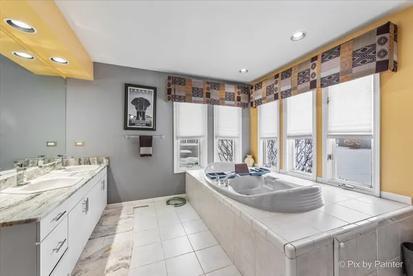 a bathroom with a sink a large mirror and a bathtub next to a window