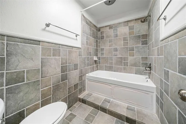 a bathroom with a white toilet and bathtub