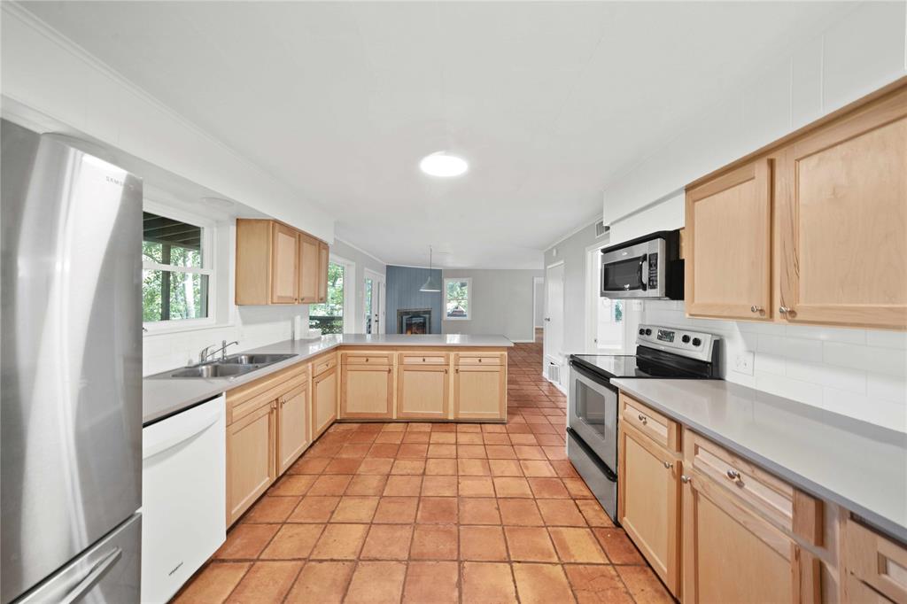 216 Pinewood Lane Hideaway, TX 75771 - Photo 8 of 40 a large white kitchen with a sink and dishwasher a stove top oven with wooden floor