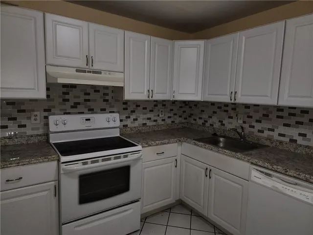 a kitchen with granite countertop white cabinets and stainless steel appliances